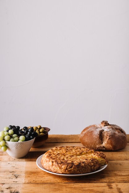 Pie and bread near grapes and olives