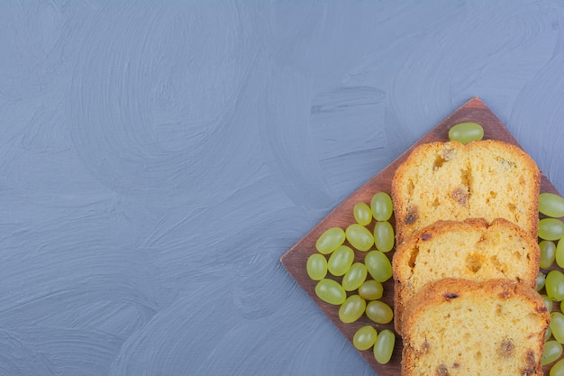 Pie slices with green grapes on a wooden platter.