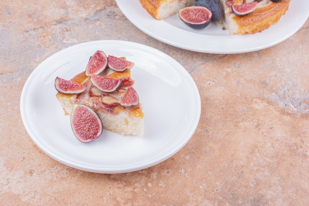 A pie with figs in a white plate on the marble