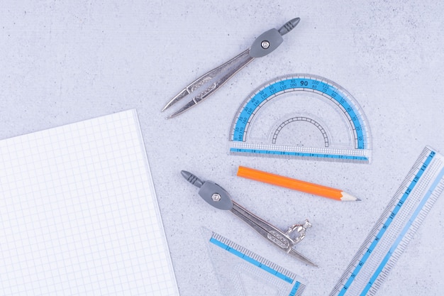 A piece of blank paper with pen, charcoal pencil, ruler and dividers around