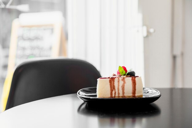 Piece of blueberry cheesecake on black plate over the wooden table