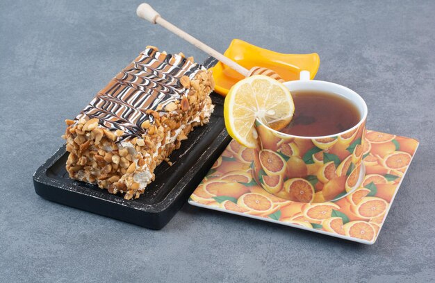 A piece of cake with cup of aroma coffee on gray surface 