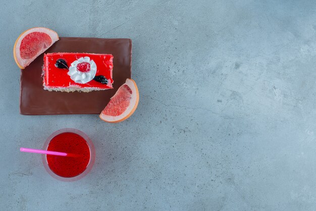 A piece of cake with a glass cup of red juice . 