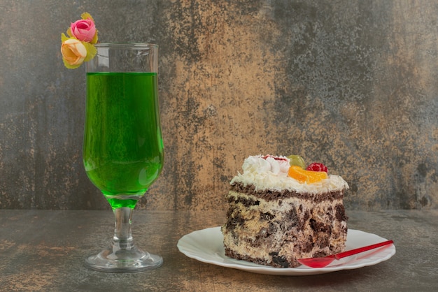 대리석 벽에 육즙이 많은 녹색 레모네이드 한 잔과 함께 케이크 한 조각