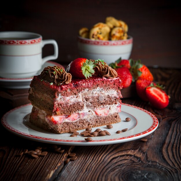 piece of cake with strawberry and crumbs and cup of tea in plate