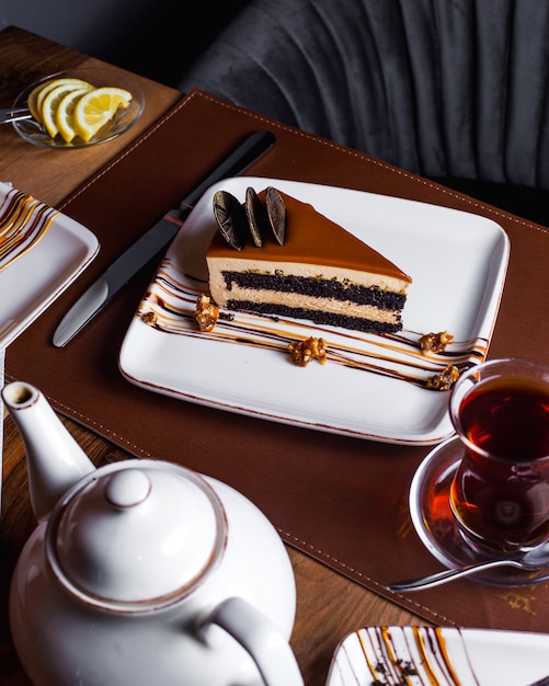 Piece of caramel cake decorated with chocolate cookies served with tea