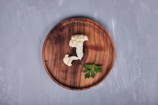 A piece of cauliflower with parsley in a wooden platter.