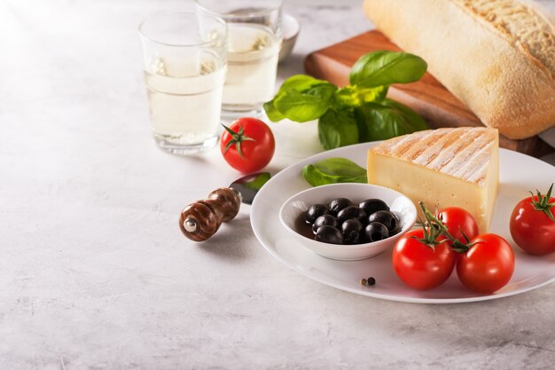 Piece of cheese with tomatoes and black olives on a plate