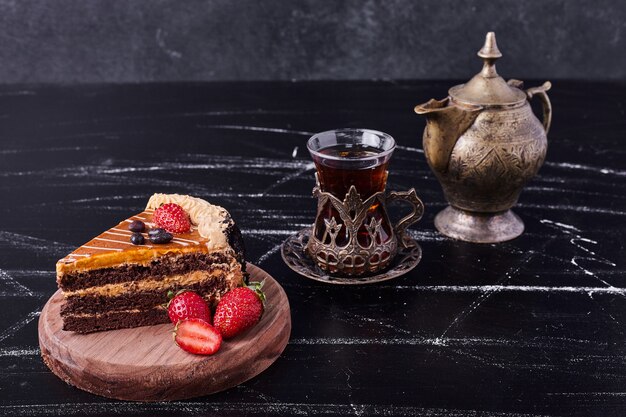 A piece of chocolate cake with classic tea set on dark background. 