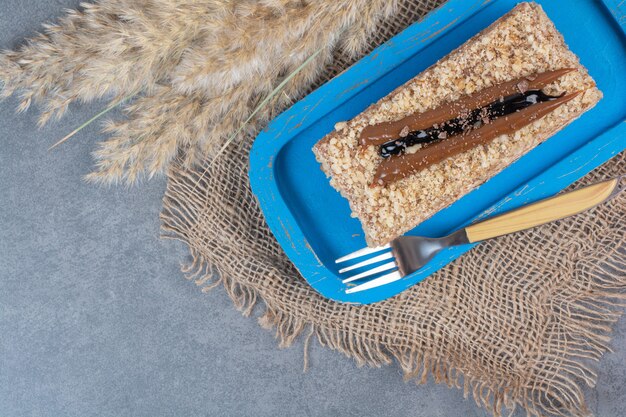 A piece of creamy cake on blue plate with fork .