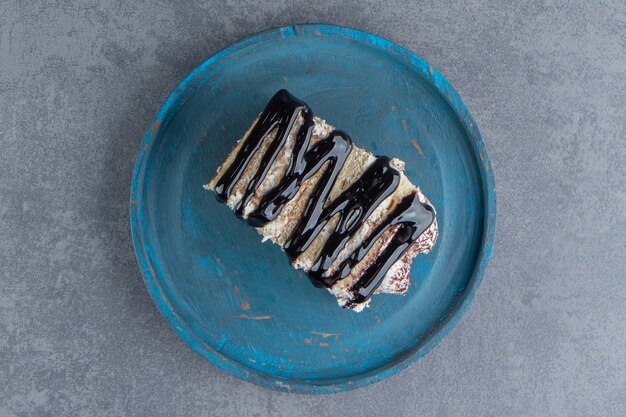 A piece of creamy cake with chocolate on a blue plate