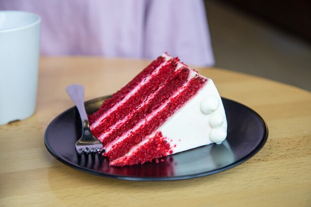 A piece of delicious red velvet cake on a plate with a fork.