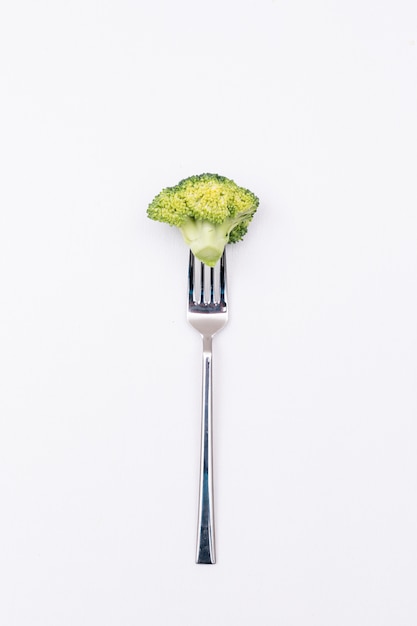 Piece of fresh broccoli on fork isolated on white surface