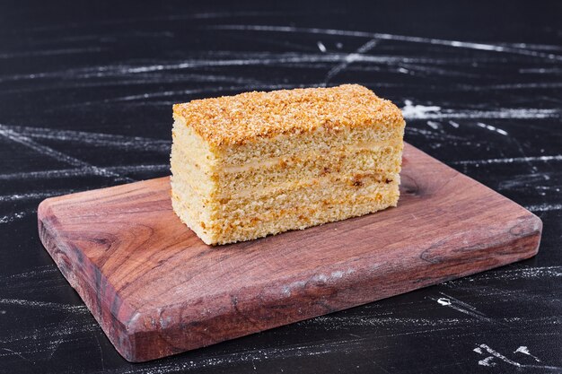 A piece of homemade honey cake on wooden board . 