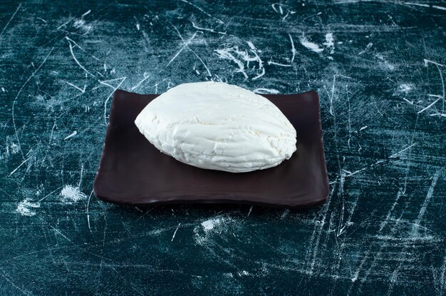 A piece of homemade white cheese on the board.