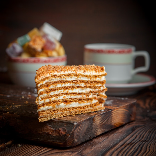 piece of honey cake with sugar and cup of tea in food board