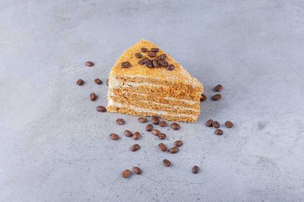 Кусок слоеного медового торта с кофейными зернами.