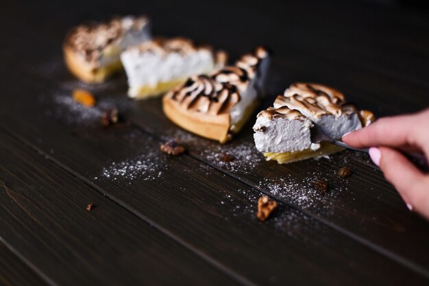 Piece of lemon cheesecake with white cream served on a dark wooden table