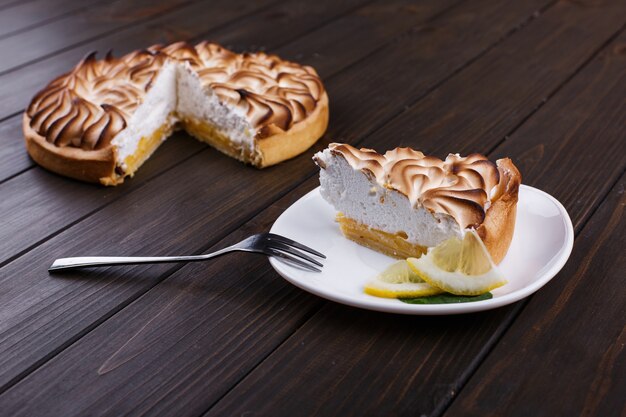 Piece of lemon pie with white cream served on white plate