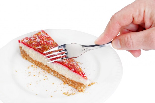 白いプレートから薄茶色のスポンジケーキの一部を取る銀のフォークで男の手の肖像画をクローズアップ 無料の写真