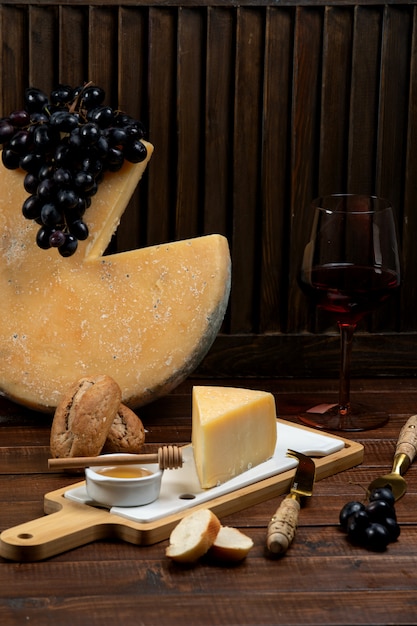 Free photo piece of parmesan cheese served with honey and grape