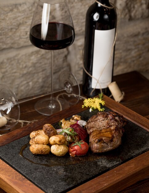 A piece of steak with round grilled tomatoes and a glass of red wine