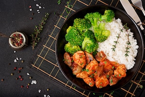 Pieces of chicken fillet with mushrooms stewed in tomato sauce with boiled broccoli and rice. proper nutrition. healthy lifestyle. dietetic menu. top view