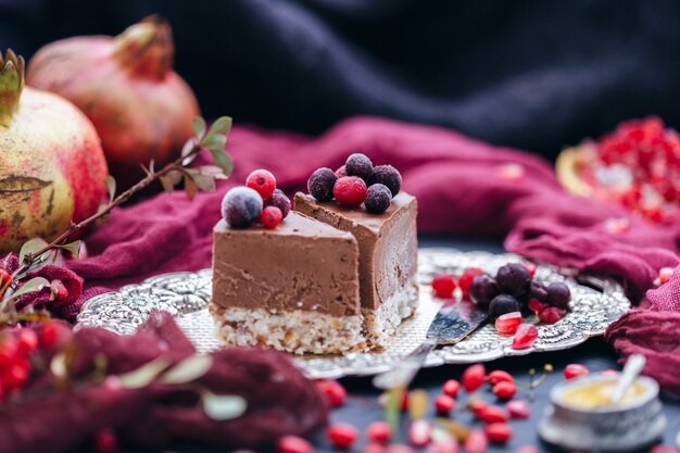 Pieces of chocolate cakes on a metal plate with berries and fruits scattered around