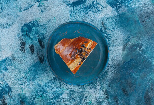 A pieces of croissant with chocolate on a wooden plate , on the marble table. 