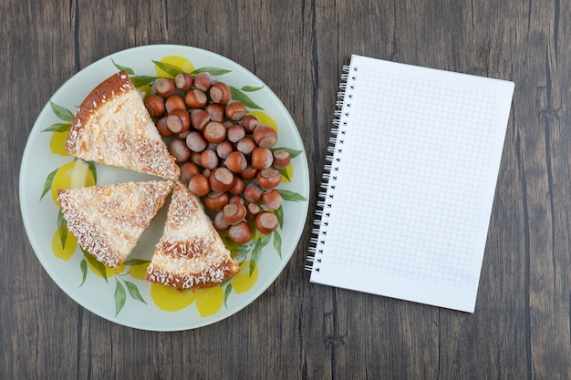 Pieces of delicious cake with macadamia nuts placed on a wooden background. 