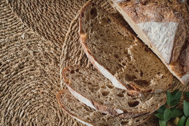 Pieces of fresh homemade sourdough bread Slicing artisan bread on a straw lining top view