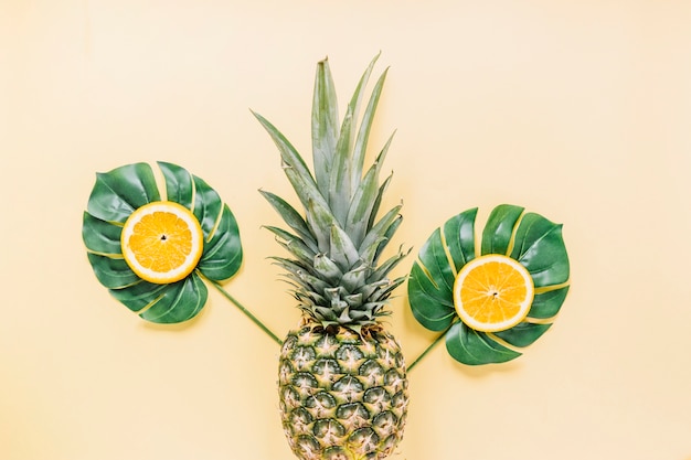 Pieces of orange on leaves near pineapple 