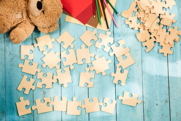 Free photo pieces of puzzles on the surface of wooden table with toys and colors