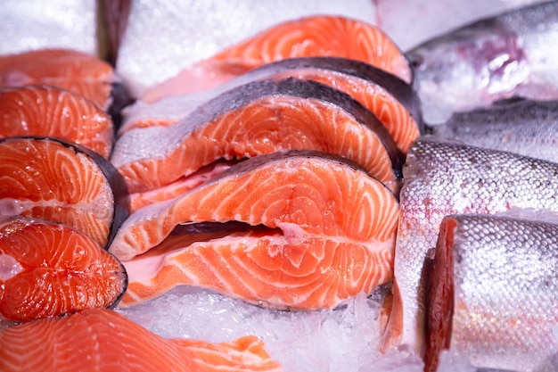 Pieces of raw steak from fresh salmon lying on the ice counter