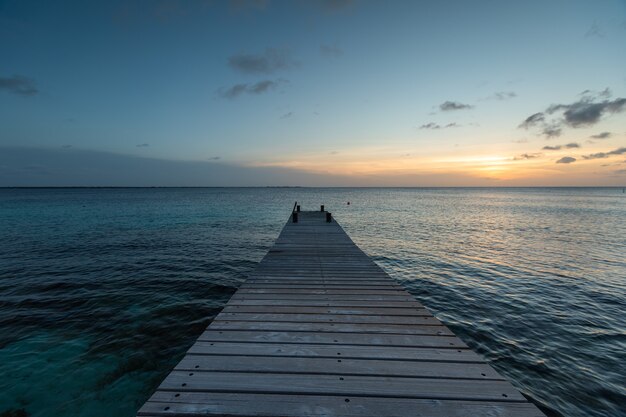 Pier leading to the breathtaking sunset reflecting in the ocean in Bonaire, Caribbean