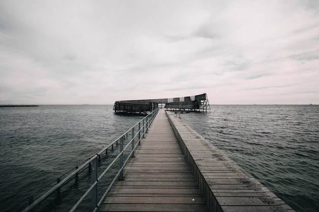 Pier leading to the ocean under the gloomy sky