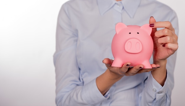 Piggy bank savings woman smiling happy. Female holding piggy ban