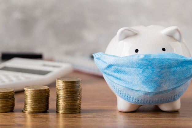 Piggy bank with medical mask and coins