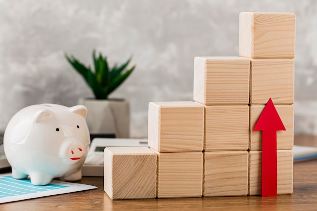 Free photo piggy bank with wooden growth blocks and arrow pointing up