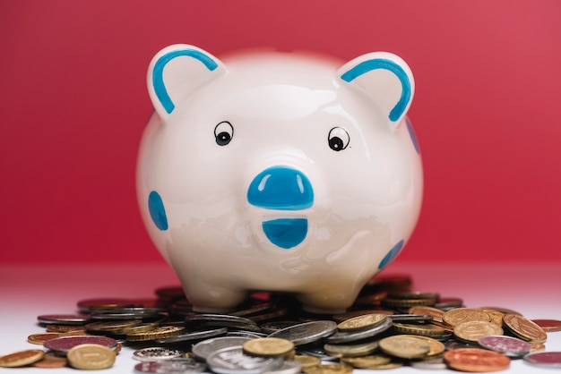 Piggybank over coins in front of red background