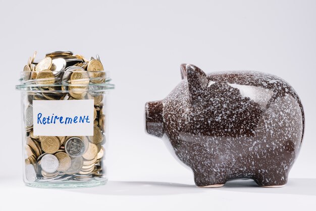 Piggybank near retirement glass container full of coins