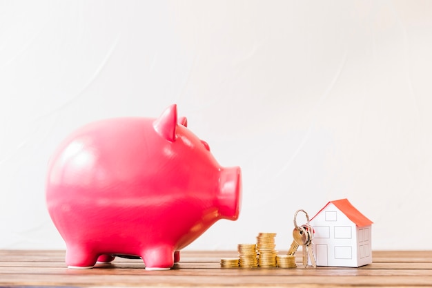 Free photo piggybank near stacked coins and house with key