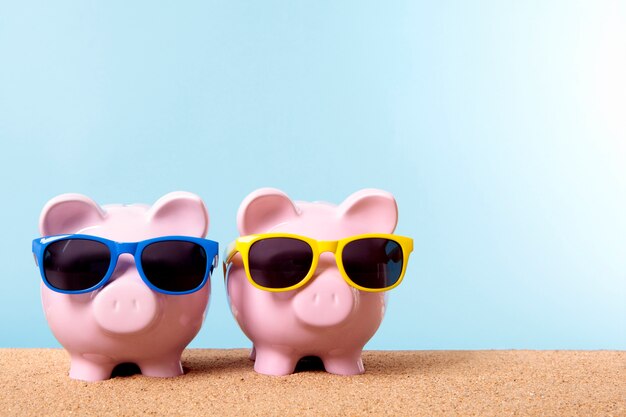 Piggybanks on a beach with sunglasses 