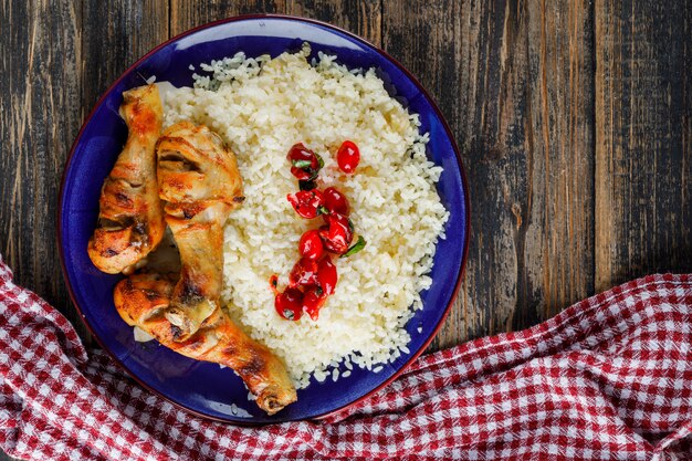 Плов в тарелке с куриным мясом, клюквой на деревянном и кухонном полотенце