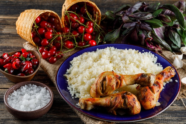 Pilaf with chicken meat, cherry, salt, basil, garlic in a plate on wooden and piece of sack high.