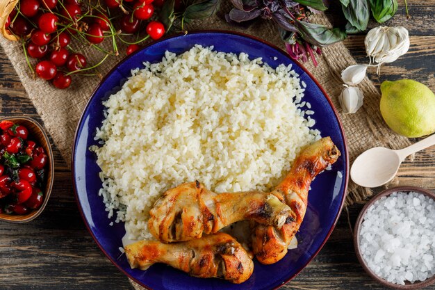 Pilaf with chicken meat, cherry, salt, lemon, basil, garlic in a plate on wooden and piece of sack.