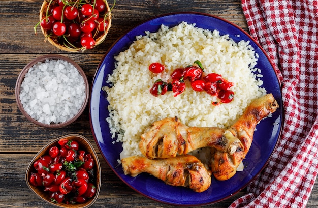 Foto gratuita pilaf con carne di pollo, ciliegia, sale in un piatto su un asciugamano di legno e cucina.