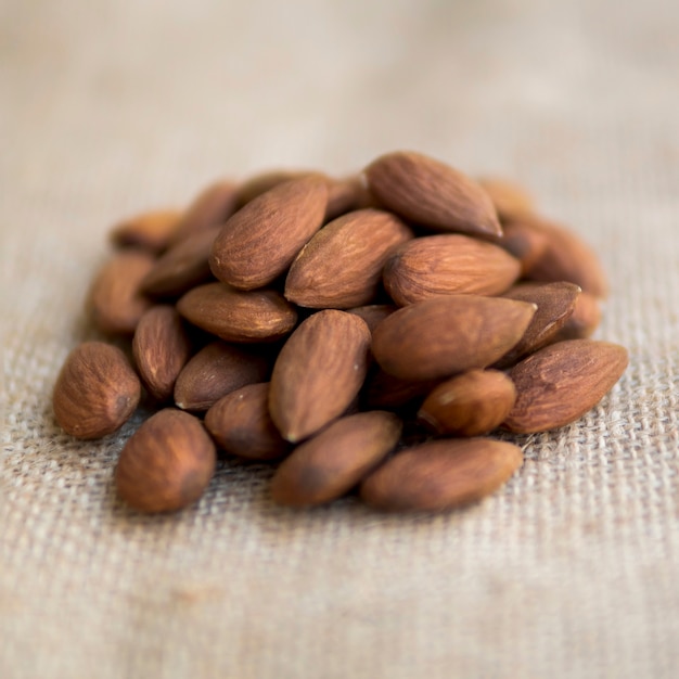 Free photo pile of almonds on beige fabric