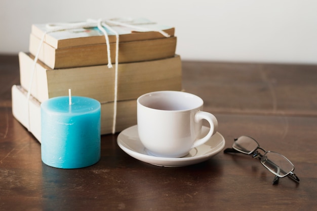 書籍、青いろうそく、コーヒー、テーブル上の眼鏡の山