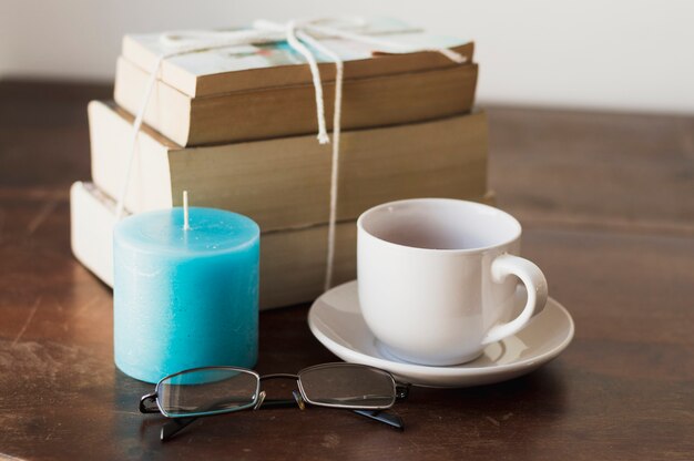 Pile of books, blue candle, coffee and glasses